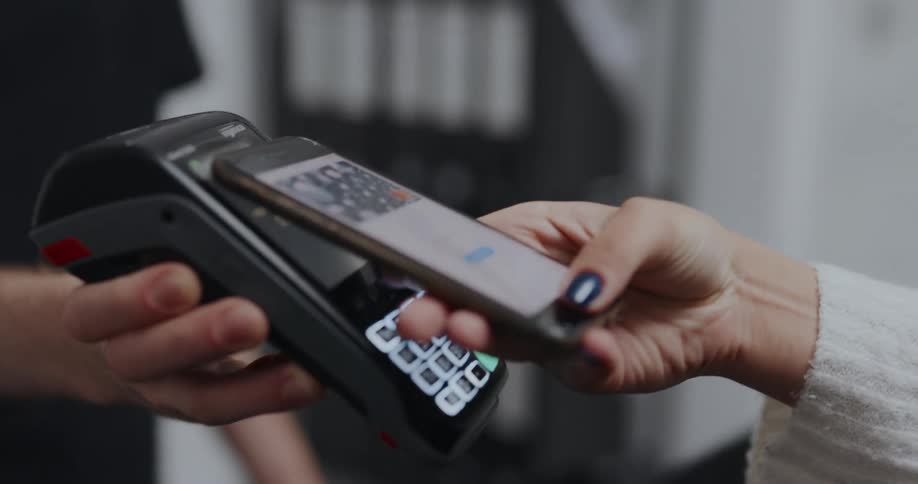 A woman presents her phone to a payment reader for a few seconds in a store