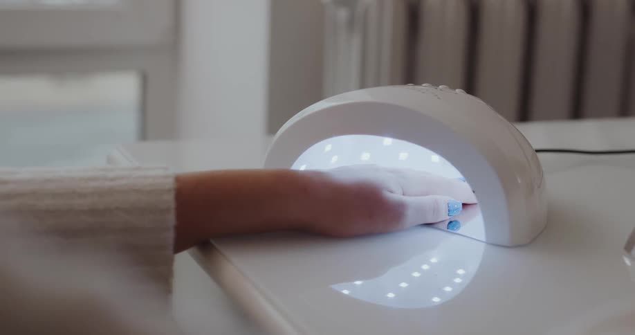 A person lays their hand in a nail dryer