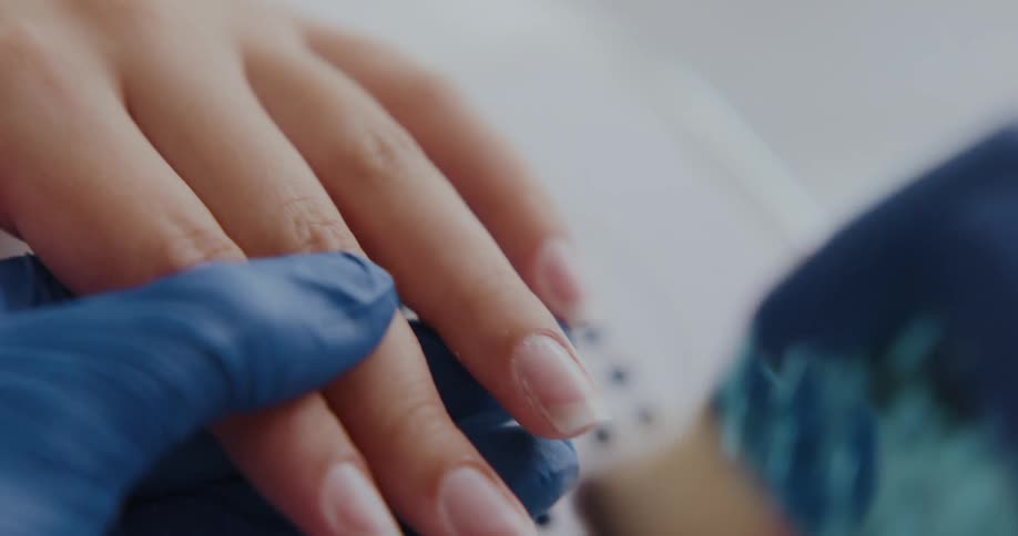 A person is using a brush on the nails of another person as they give a manicure