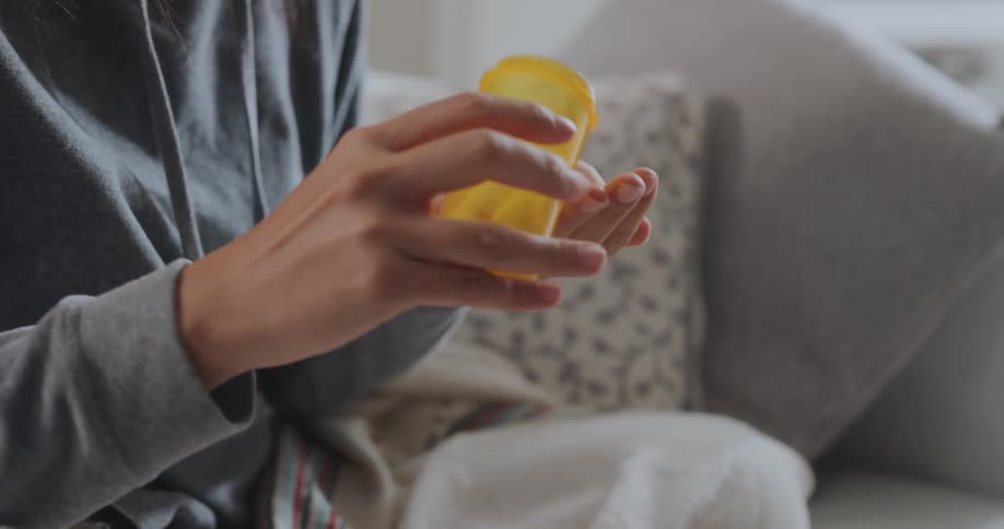 Young woman is opening pill bottle