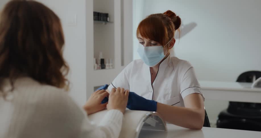 A woman sits down to have her nails done