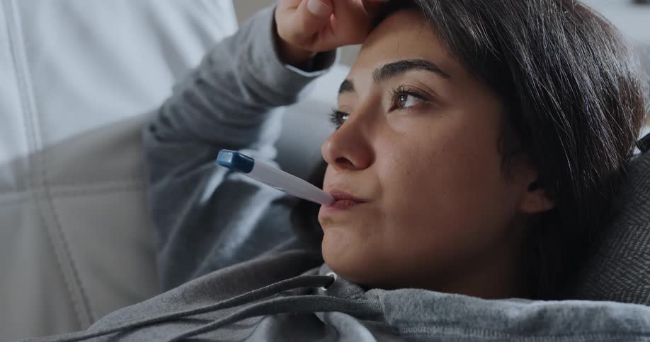 A woman takes her temperature with a thermometer