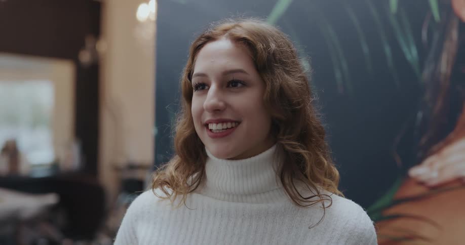 A young woman nods and smiles while chatting to someone in front of a large poster in a store