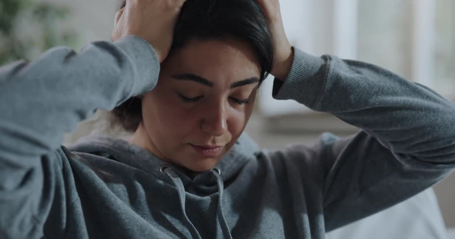 Young sick woman with a headache rubs her head and forehead with her hands