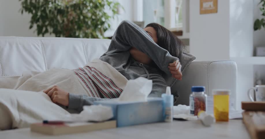 Young woman is laying down and coughing