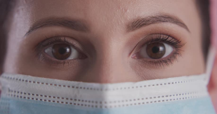 Female model with brown eyes and blue mask faces the camera with eye contact