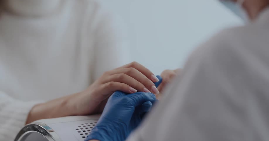 Both manicurist wear face masks as they talk during a manicure
