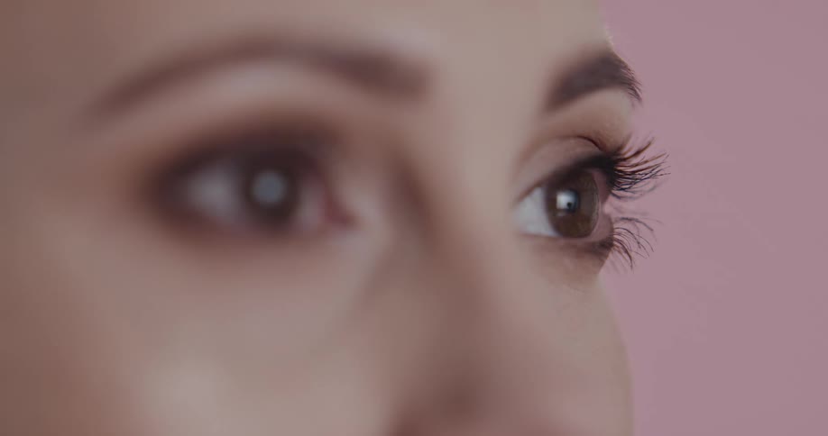 Close up of the eyes of a woman standing in front a pink background