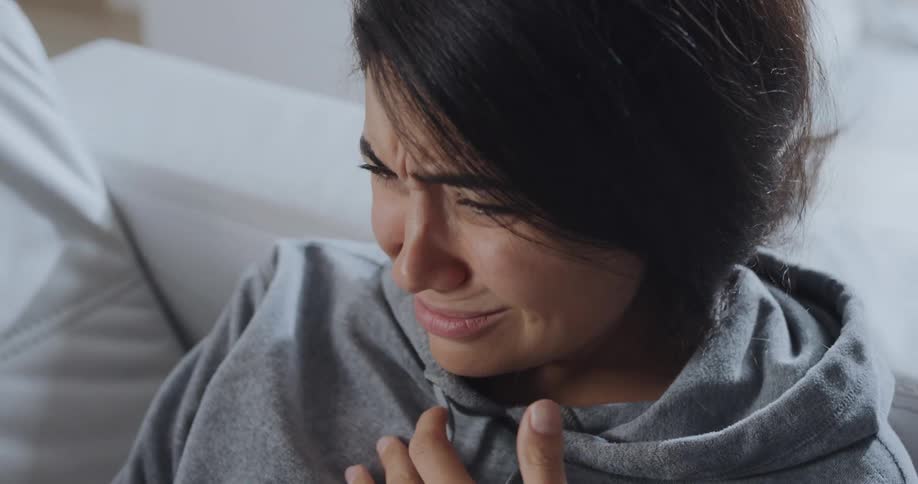 A woman is sitting on a couch and talking to someone