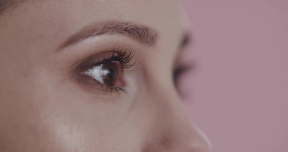 Close up of the eyes of a woman standing in front a pink background