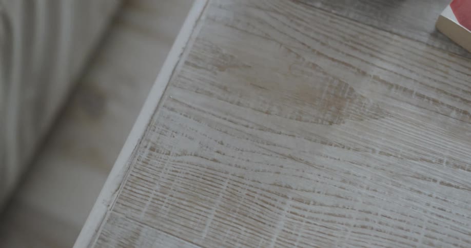 A person picks up and takes a thermometer from off of a wooden table