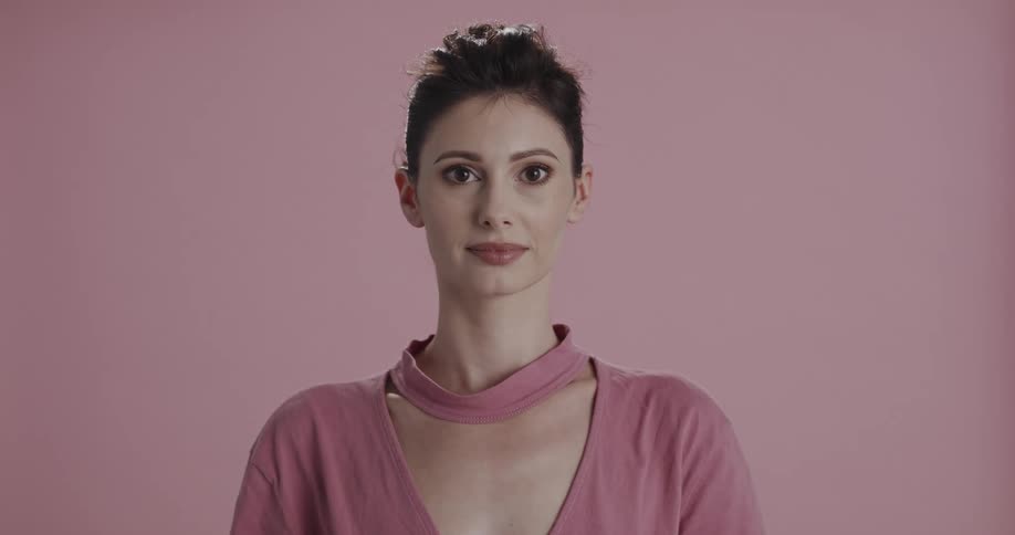 A woman in pink clothing raises her eyes to gaze into the camera