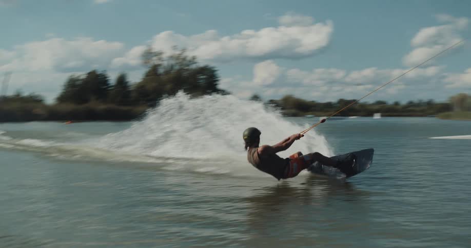 Man wearing helmet cable water skis across rippling water