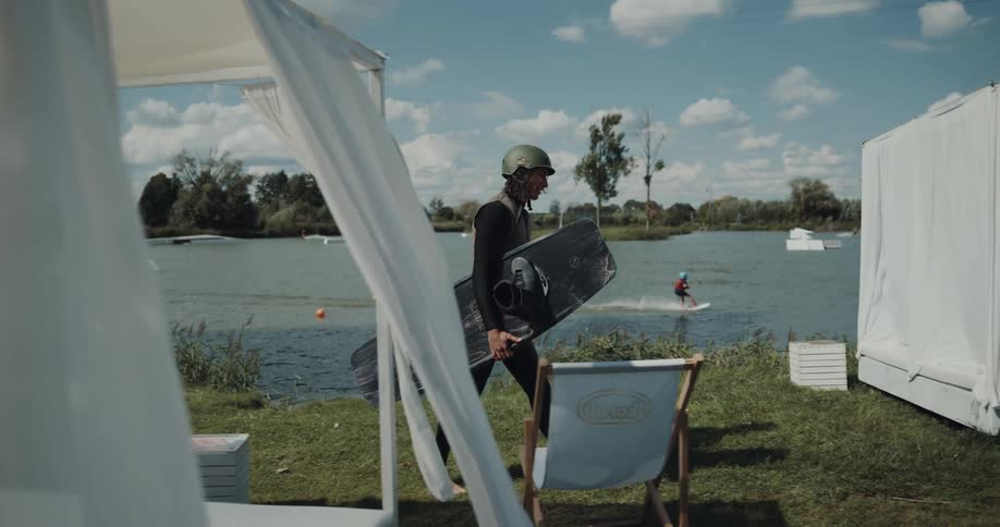 A man carries his wakeboard by the lake