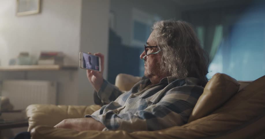 Old man is sitting on a chair and on there phone