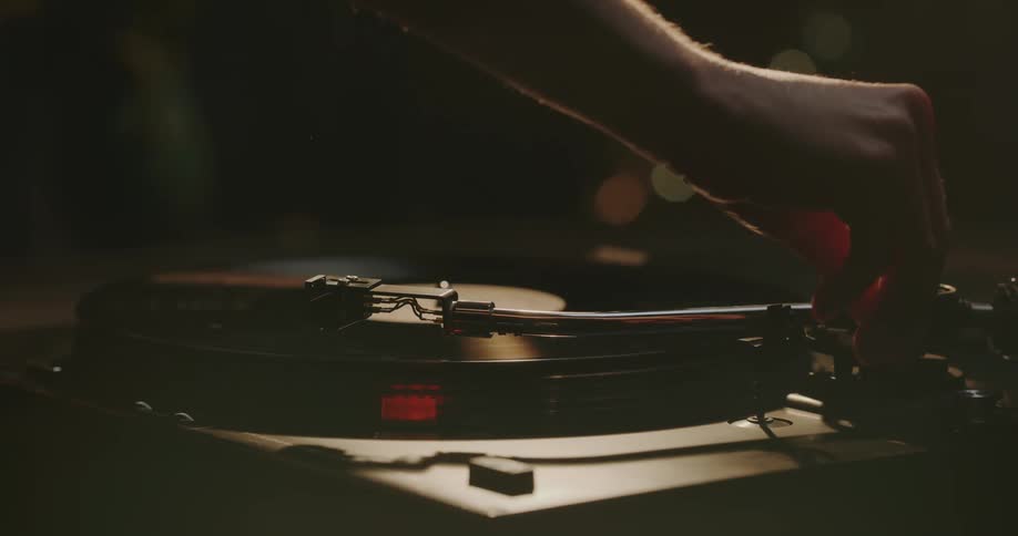 Someone puts a vinyl record on an old turntable and places the needle on the record