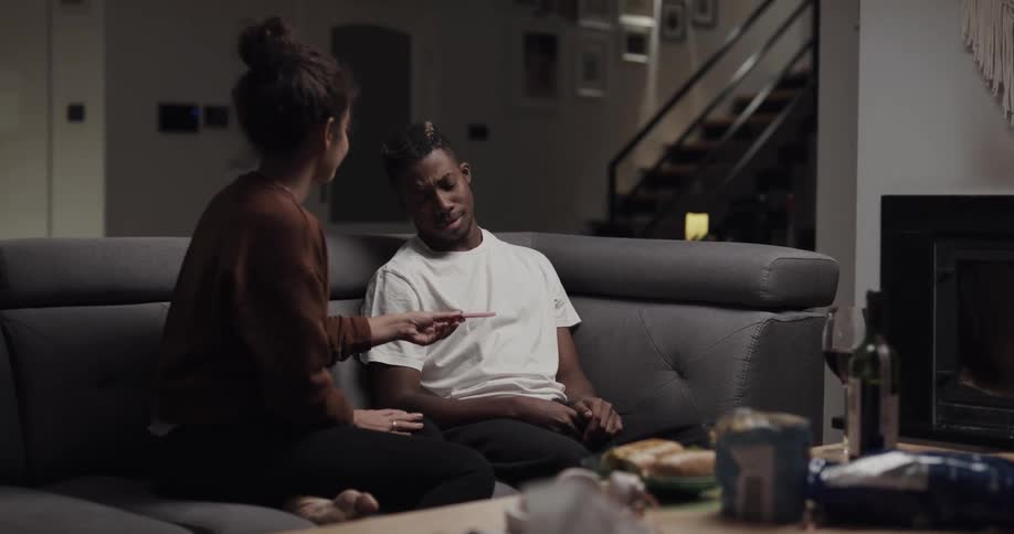A woman interrupts a man playing video games