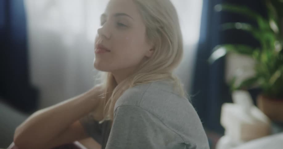 Young blonde woman is sitting on a bed