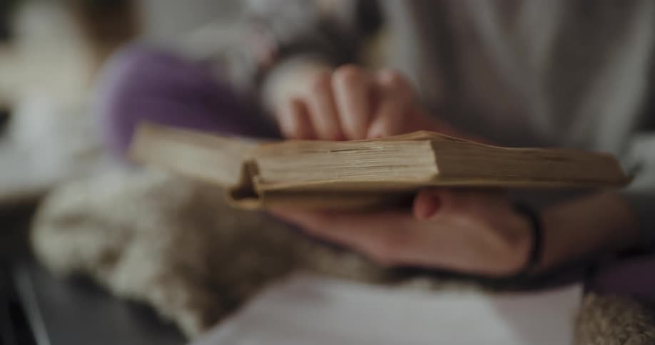 A person flips through the pages of an old book before closing it