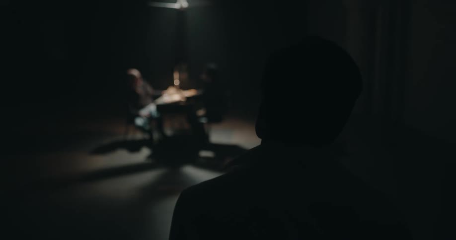Silhouette of a man looking an active interrogation inside a dimly lit room