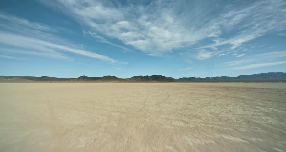 Flat plains of a desert close to the mountains under a blue sky