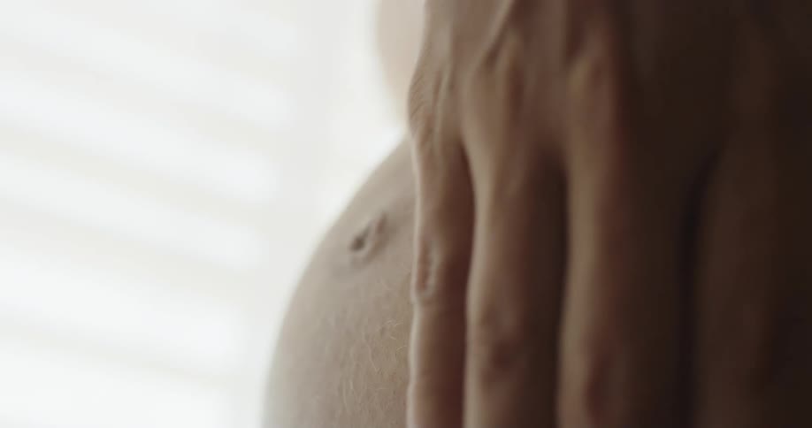 A woman rubs her pregnant belly