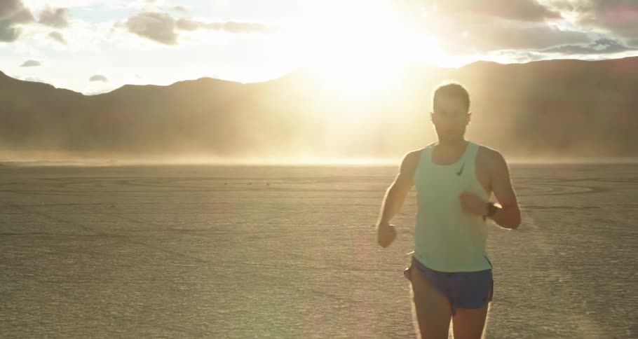 A man jogs through a flatland in a desert during the day