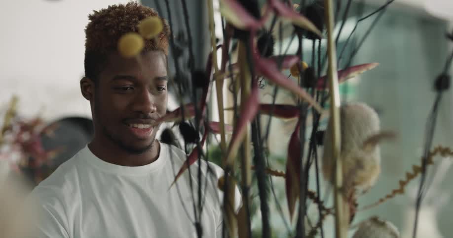 A man is smiling while arranging flowers in a flower shop