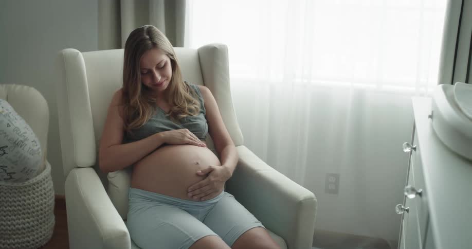 Pregnant women is sitting down on a chair