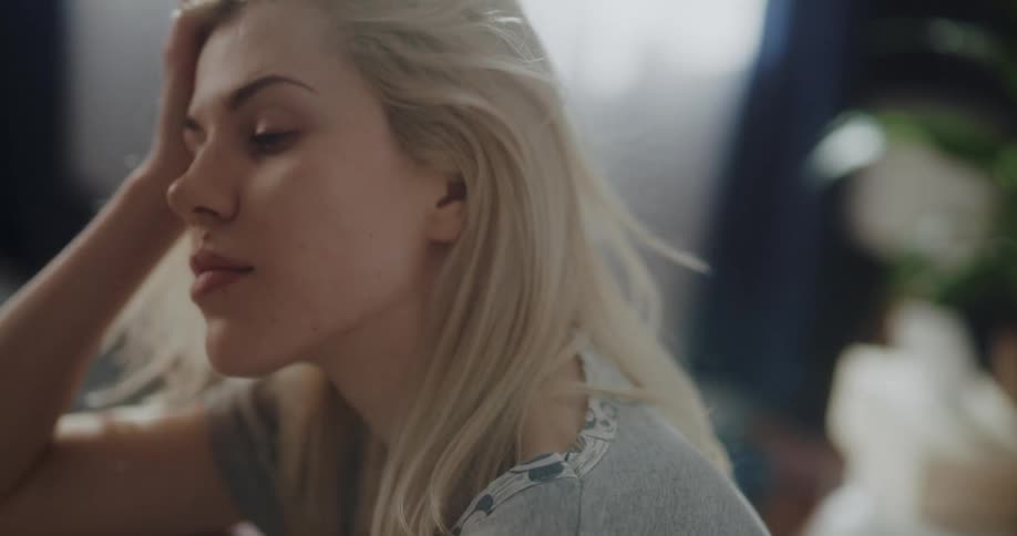 A woman brushes her hair and wipes her face