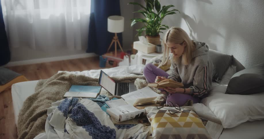 A woman is studying looking through books and taking notes