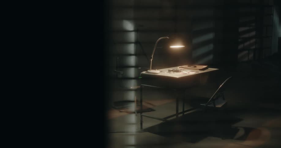 Desk lamp shines a light over a desk inside an interrogation room