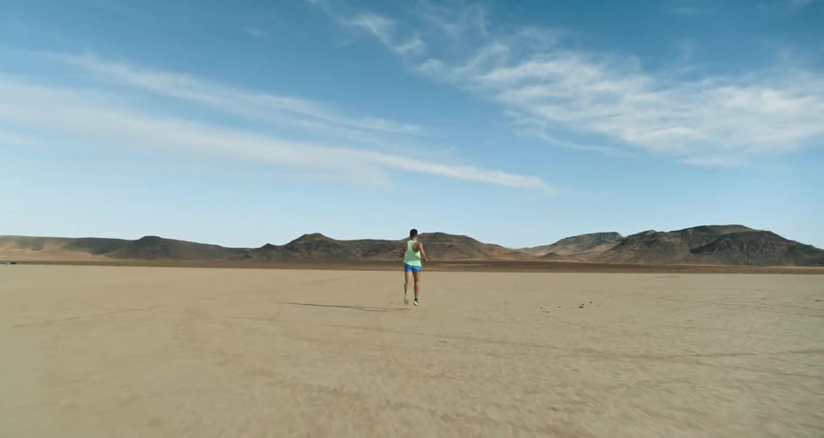 A man jogs through a flatland in the desert during the day