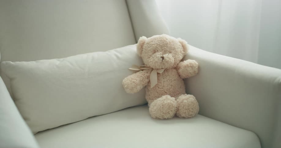 A teddy bear sitting on a rocking chair indoors during the day