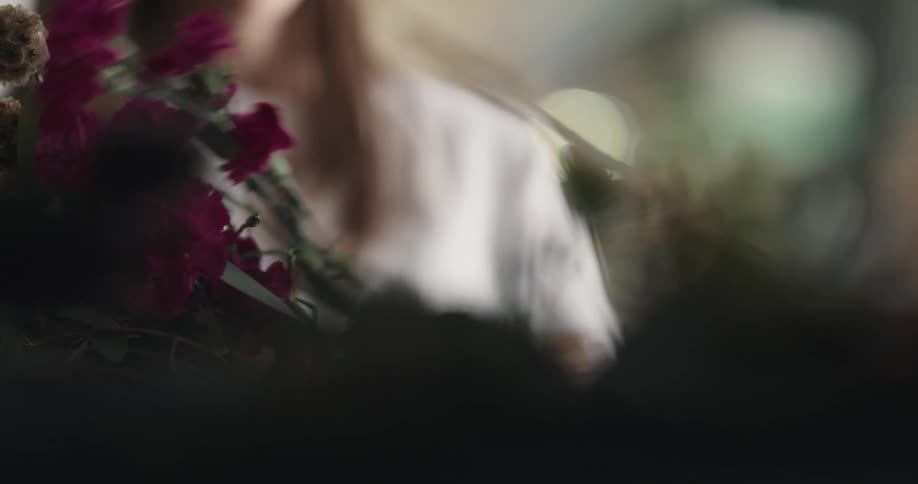 Two women are arranging flowers into a bouquet
