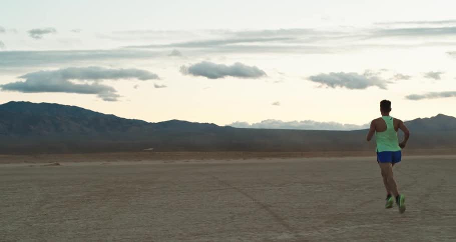 A man jogs through a flatland in the desert during the day