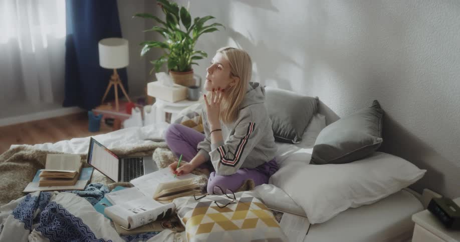 Young woman is sitting on the bed working