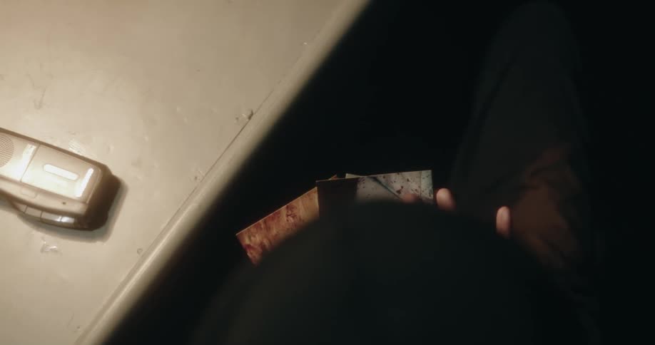 Man picks up photographs from a table inside a dimly lit room