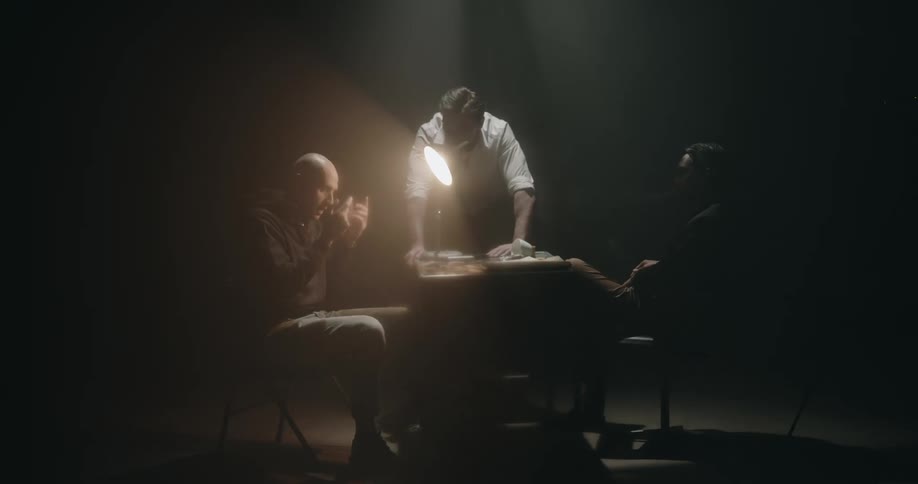 A police officer slams his hand on the table during an interrogation