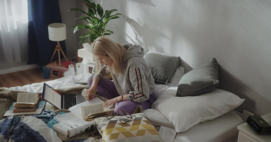 Young blonde woman sitting in front of a laptop studying at home