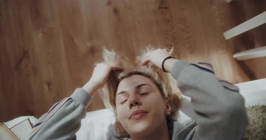 Young woman is playing with her hair in bed