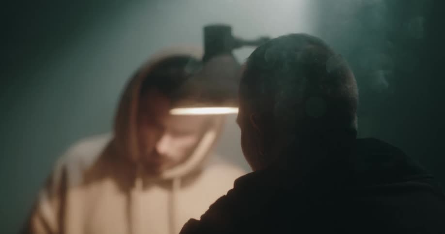 A handcuffed man looks at a photo