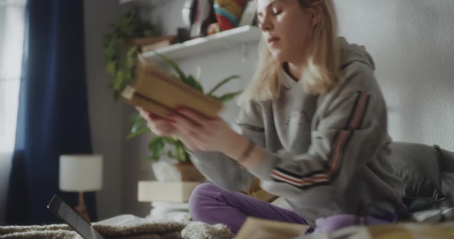 Young blonde woman sitting on the bed at home studying