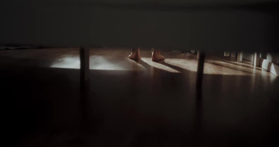 Barefoot person steps onto floor and walks away from furniture