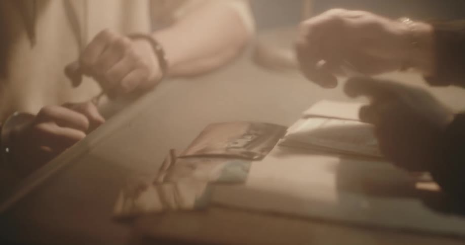 Male member of law enforcement hands pictures to cuffed suspect