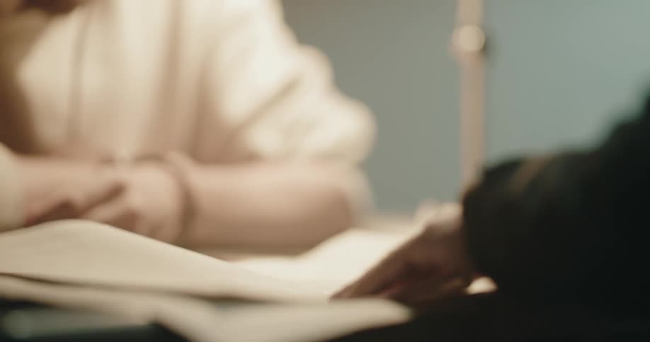 Two people are talking at a table and looking at paper