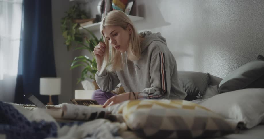 Young women is sitting on the bed working