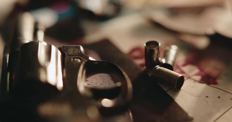 Shell casings and revolver lie on floor smeared with red