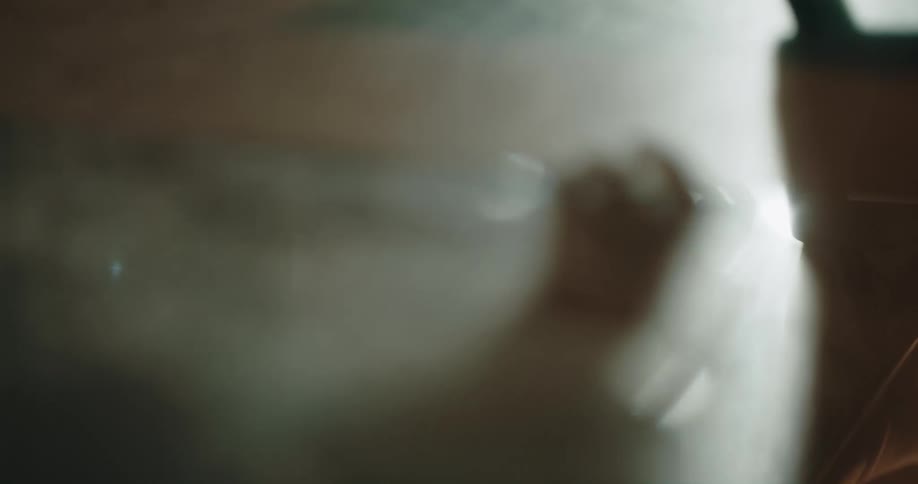 A person scratches and hits their hands against frosted glass