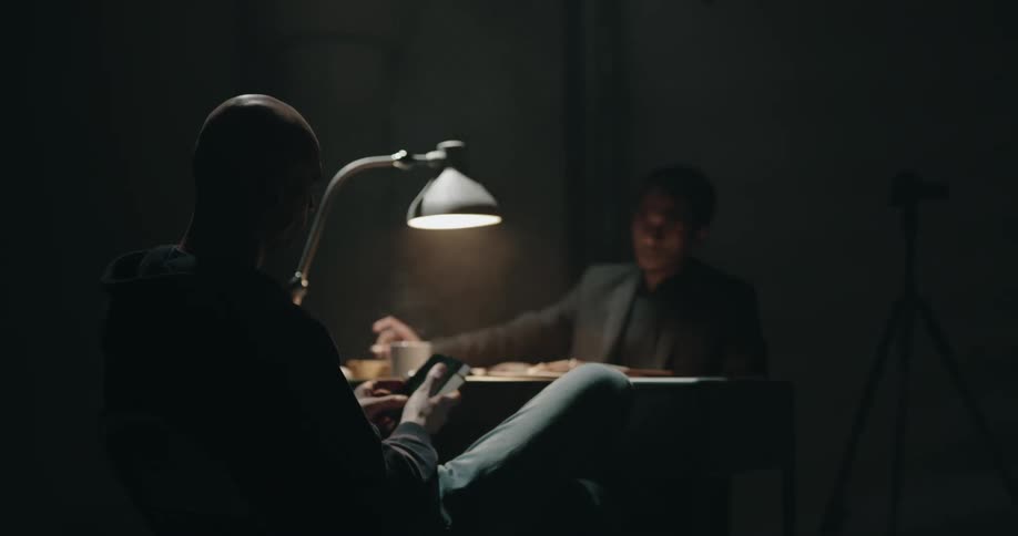 Detective shows pictures to a suspect sitting inside an interrogation room